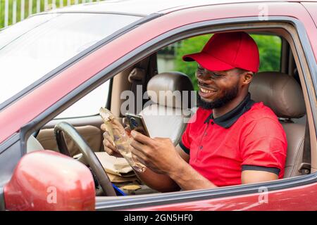 delivery worker using his phone, sitting inside a car Stock Photo
