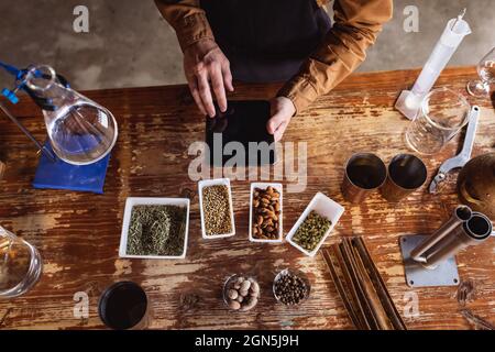 Close up view of hands using digital tablet and multiple ingredients on a wooden table Stock Photo