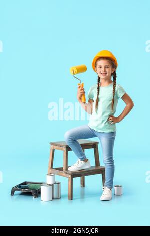 Little girl with paint roller on blue background Stock Photo