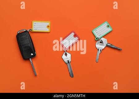 Different keys with plastic tags on orange background Stock Photo