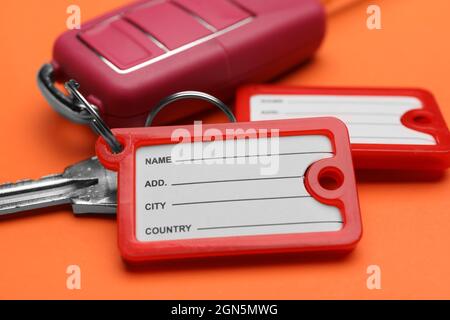 Different keys with plastic tags on orange background, closeup Stock Photo