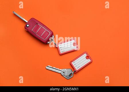 Different keys with plastic tags on orange background Stock Photo