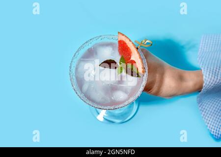 Woman holding glass of tasty grapefruit margarita on color background Stock Photo