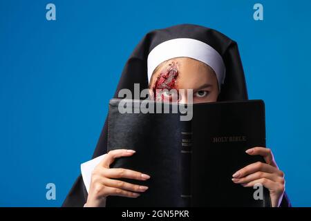 Woman dressed for Halloween as nun with Bible on color background Stock Photo