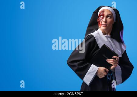 Woman dressed for Halloween as nun with Bible on color background Stock Photo