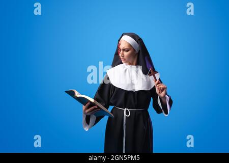 Woman dressed for Halloween as nun with Bible on color background Stock Photo