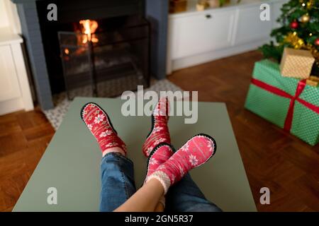 Feet of caucasian couple wearing christmas socks and sitting on sofa at christmas time Stock Photo