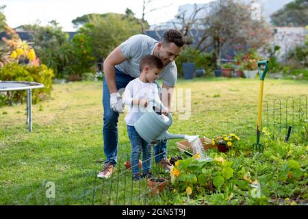 Happy caucasian father and son watering plants together Stock Photo