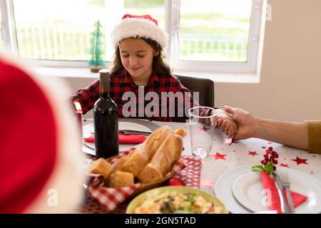 Caucasian girl and wearing santa hat praying at christmas table Stock Photo