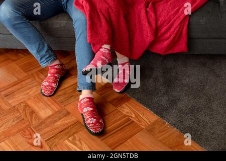 Legs of caucasian couple sitting on sofa with blanket in christmas socks Stock Photo