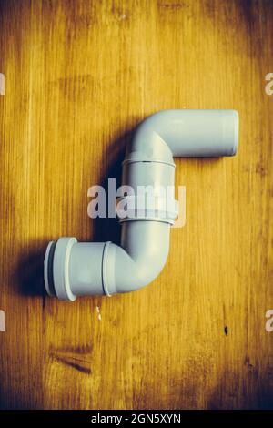 Close up shot of some PVC pipes with connectors, on a wooden background. Stock Photo