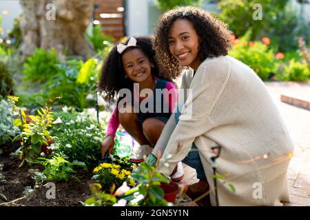 Happy african american mother and daughter planting flowers Stock Photo