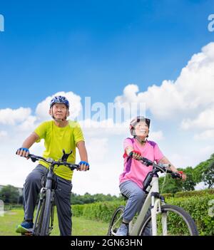 Asian healthy senior couple exercising with bicycles Stock Photo