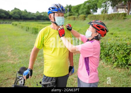 Senior couple  wearing medical mask and riding bicycle in the park Stock Photo
