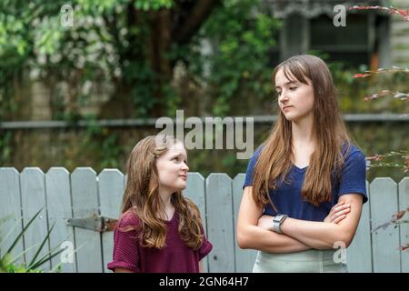 Two sisters and one is a teenager not happy with her little sister Stock Photo