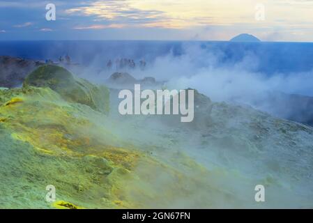 Hikers walking through fumaroles smoke on Gran Cratere rim, Vulcano Island, Aeolian Islands,  Sicily, Italy, Stock Photo