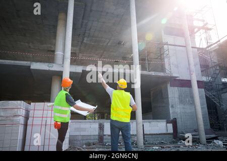 Engineer discussing with foreman about project in building construction site. Stock Photo