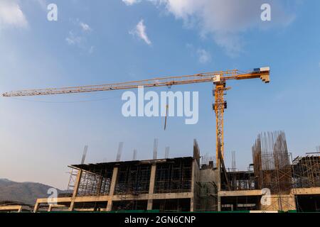 Yellow tower crane and building under construction against blue sky. Industry concept. Stock Photo