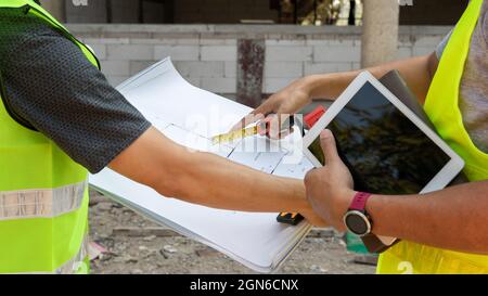 Engineer discussing with foreman about project in building construction site. Stock Photo