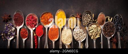 Various spices in vintage spoons on stone table. Top view flat lay Stock Photo