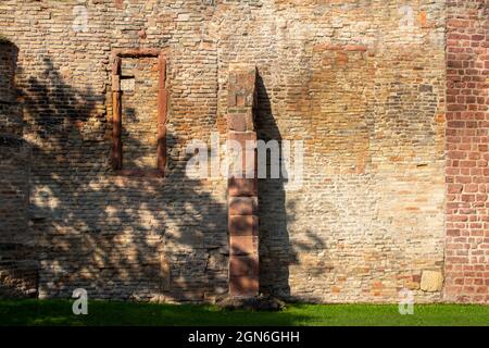 Tan color European medieval stone wall background, with view of a window frame and supporting column in bright sunlight Stock Photo