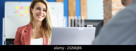 Smiling businesswoman communicates with her male colleague at work Stock Photo