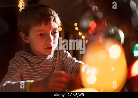 Portrait of 8 years old boy decorating Christmas tree Stock Photo