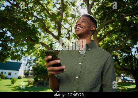 Mixed race male farmer standing outdoors holding cellular device Stock Photo