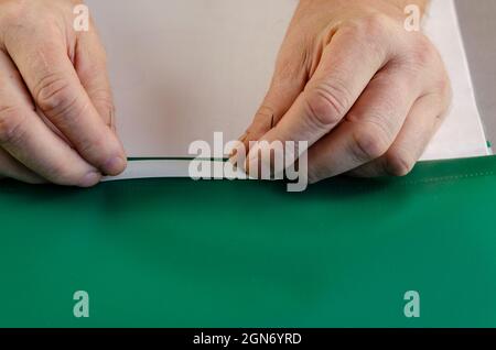 Two hands hold a green file folder with a binder on a gray surfa Stock Photo