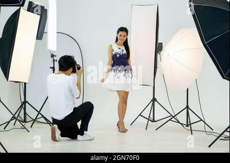 Young asian photographer is photographing a model posing in the studio. Stock Photo