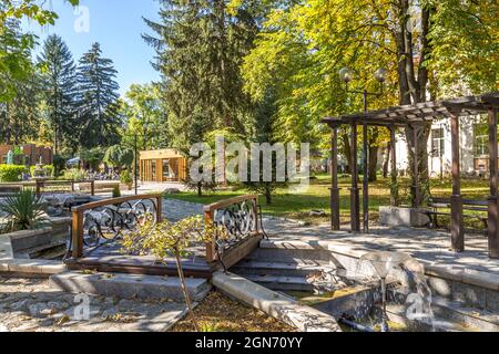 Razlog, Bulgaria - October 20, 2020: Downtown street panoramic view with cafe, autumn trees and fountains Stock Photo