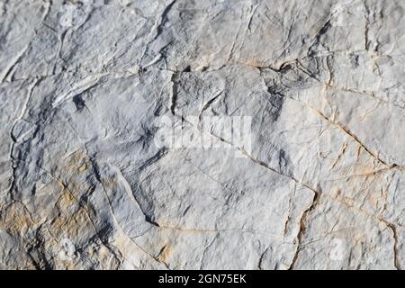 White big marble rock material with cracks close-up texture. Light stone surface pattern details in sunny Greece Stock Photo