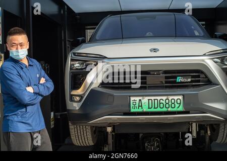 A worker stands beside a NIO electric SUV at a NIO Power station in Beijing, China. 23-Sep-2021 Stock Photo