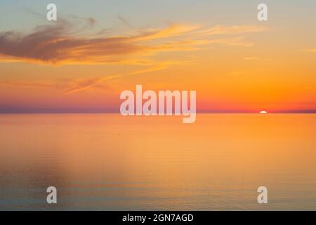 Sun going down at sunset over a calm sea Stock Photo