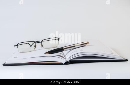 Diary, glasses and pen on white background. Business concept Stock Photo