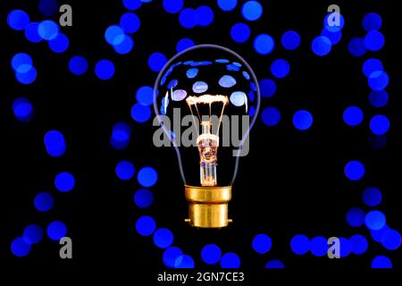 Soft glowing light bulb with black background with blue dots Stock Photo