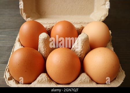Six of Organic Chicken Eggs in Paper Carton Box on Dark Brown Wooden Background Stock Photo