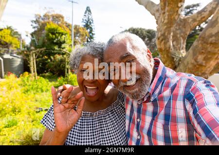 Happy african american senior couple taking selfie in garden Stock Photo