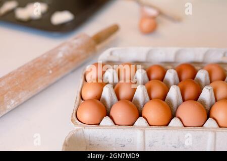 Box full of eggs and rolling pin lying on table in kitchen Stock Photo