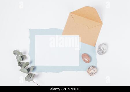 Template blank greeting card with envelope, stones and eucalyptus branch on white background Stock Photo