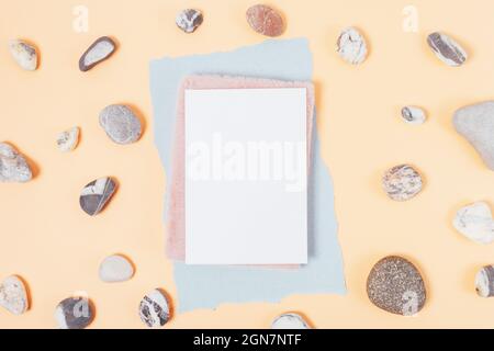 Blank white sheet template with notebook on beige background with natural stones, flat lay Stock Photo