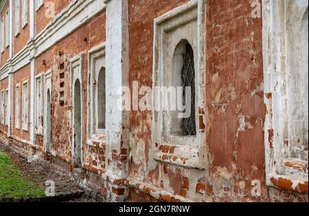 old shabby facade of the building. Weathered and red painted cement and brick wall. Painted distressed wall surface Stock Photo