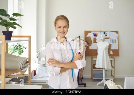 Portrait of confident and smiling seamstress woman standing in sewing workshop looking at camera Stock Photo