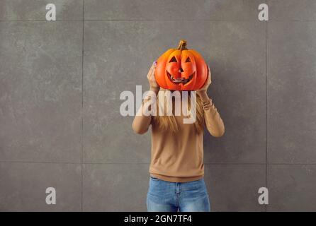 Young woman holding carved Jack-o-lantern pumpkin that she has made for Halloween party Stock Photo