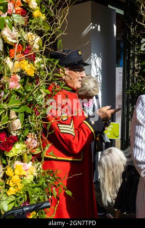 A red-coated Chelsea Pensioner at a Fairtrade stand, RHS Chelsea Flower Show, held in Royal Hospital Chelsea grounds, London, September 2021 Stock Photo