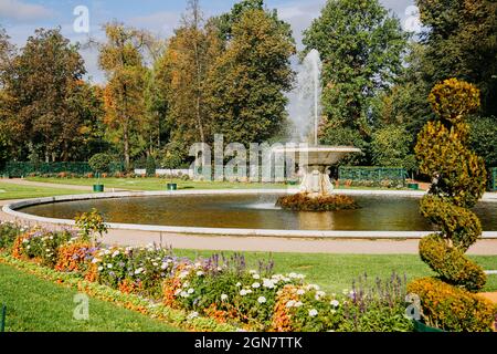 Beautiful fountain on a summer day. Bright green park with blooming flowers. Sunny day Stock Photo