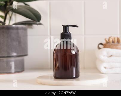 Brown bottle mockup for bathing products in bathroom, spa shampoo, shower gel, liquid soap on marble podium and various accessories front view. Stock Photo