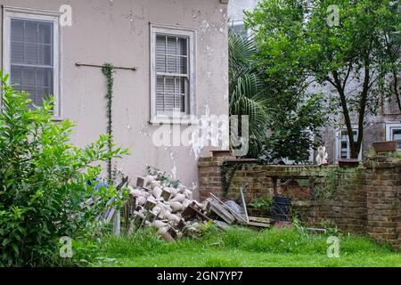 NEW ORLEANS, LA, USA - JULY 6, 2021: Rubble pile in backyard of house guarded by cat on a brick wall Stock Photo