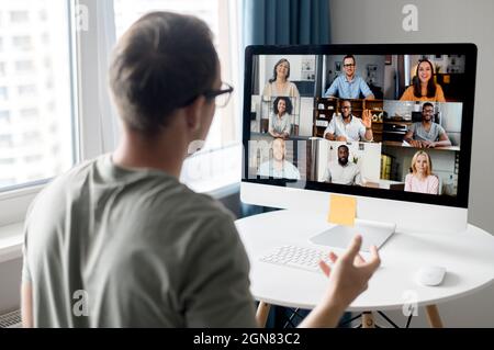 View from back above male shoulder on the laptop with diverse employees, coworkers on the screen, video call, online meeting. App for video conference with many people together Stock Photo