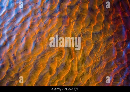 Clear golden water stream pattern with sand waves under it Stock Photo
